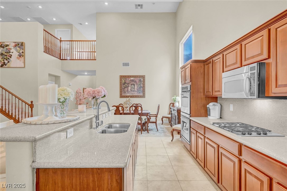9725 Sandy Turtle Avenue Las Vegas, NV 89149 - Photo 20 of 51 Kitchen with a towering ceiling, light stone countertops, light tile patterned floors, brown cabinets, and recessed lighting