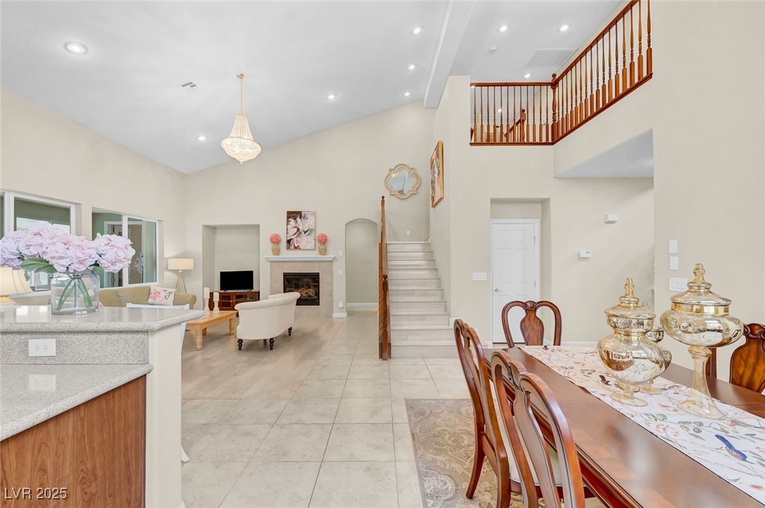9725 Sandy Turtle Avenue Las Vegas, NV 89149 - Photo 22 of 51 Dining space with high vaulted ceiling, a tiled fireplace, light tile patterned floors, recessed lighting, and stairway