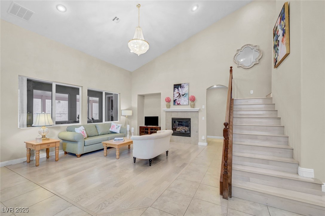 9725 Sandy Turtle Avenue Las Vegas, NV 89149 - Photo 5 of 51 Living room with stairs, a fireplace, light tile patterned floors, high vaulted ceiling, and arched walkways