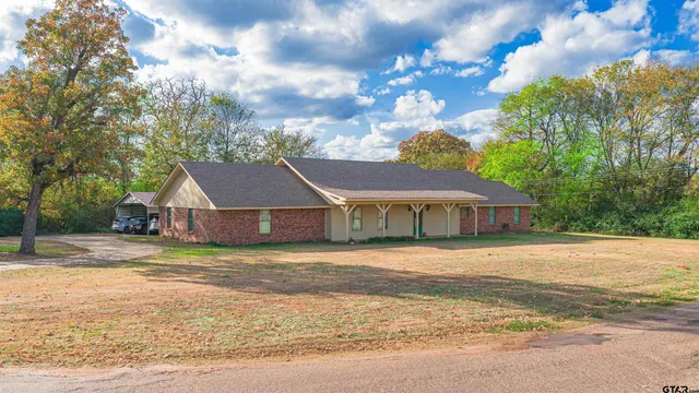 a front view of house with yard and trees in the background