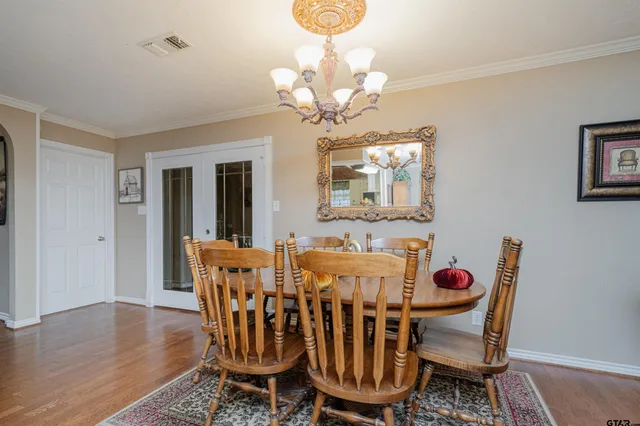 a dining room with wooden floor a chandelier a wooden table and chairs