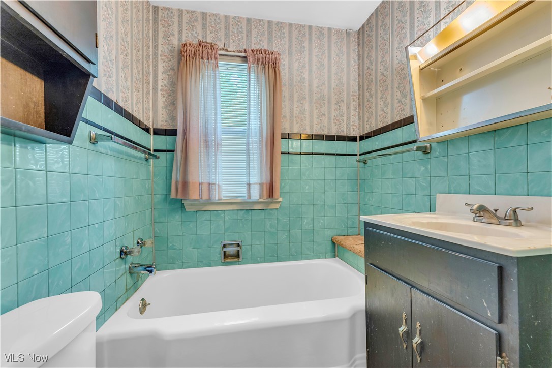 12931 Fruitside Road Garfield Heights, OH 44125 - Photo 11 of 15 Bathroom featuring tile walls, toilet, a bathing tub, and vanity