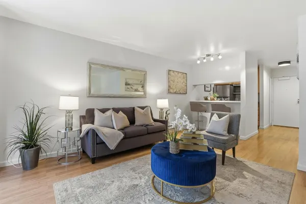 a living room with furniture potted plant and kitchen view