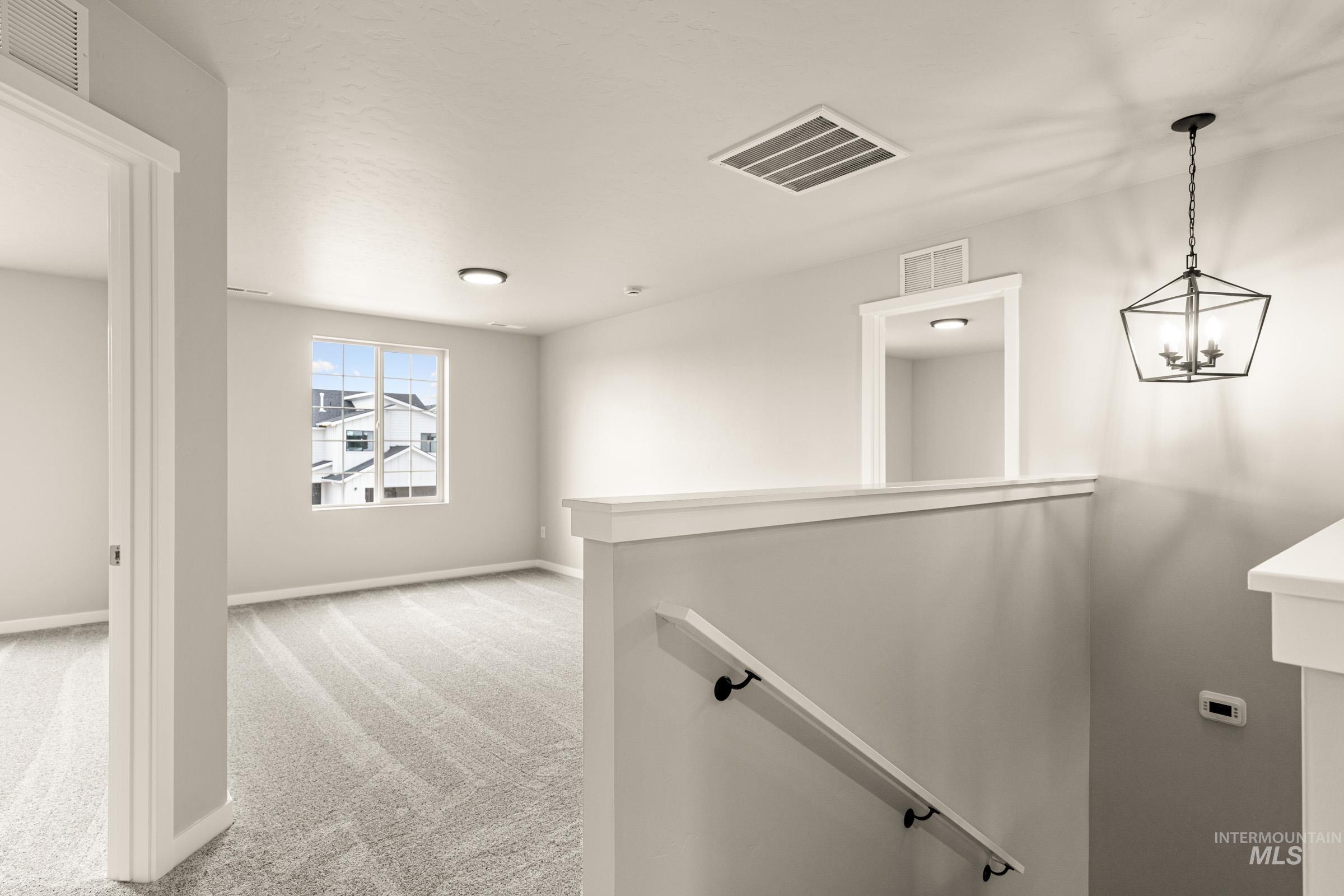 13686 Inman Court Caldwell, ID 83607 - Photo 15 of 20 Hall with light carpet and a chandelier