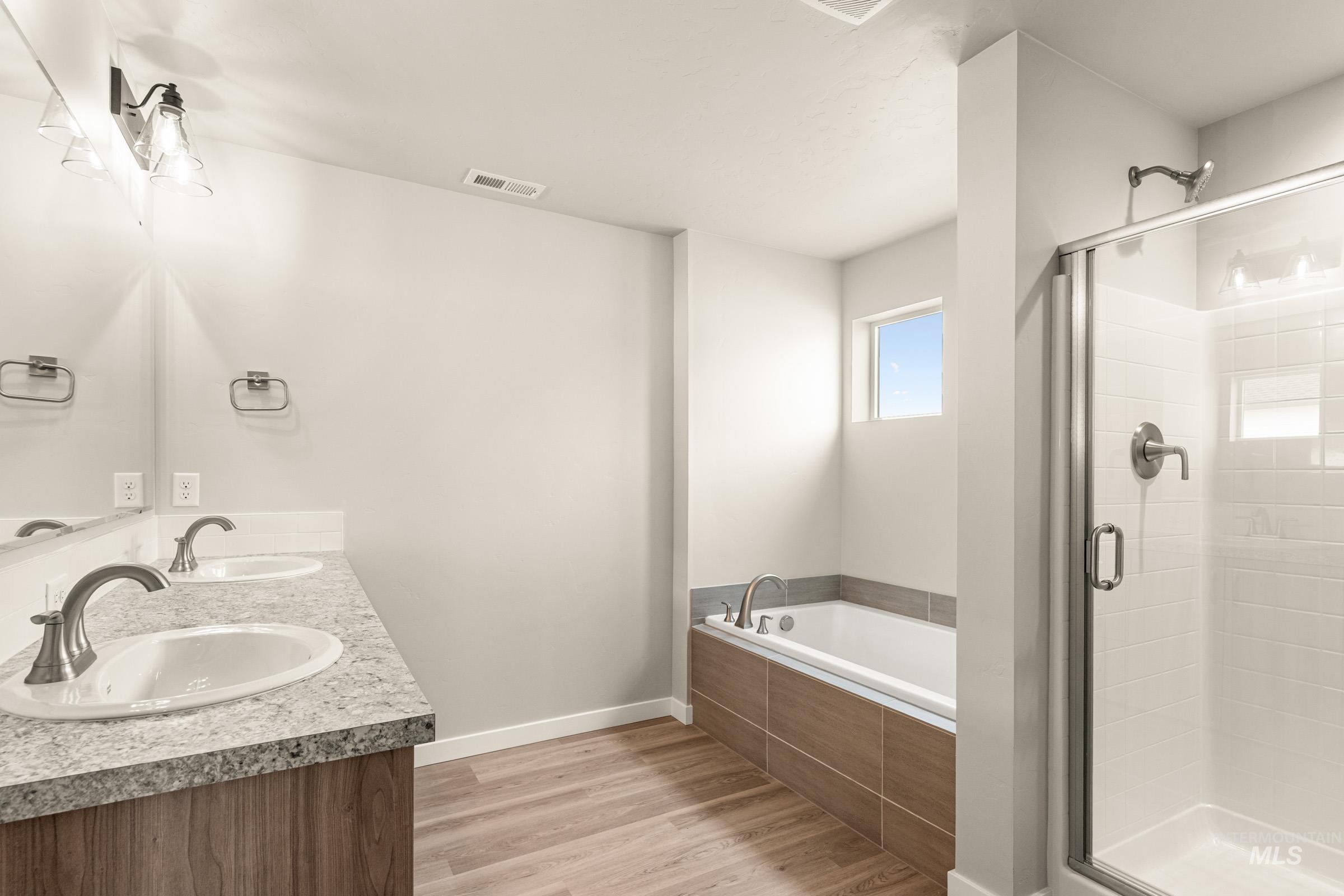 13686 Inman Court Caldwell, ID 83607 - Photo 19 of 20 Bathroom featuring light wood-style flooring, a shower stall, a bath, and double vanity