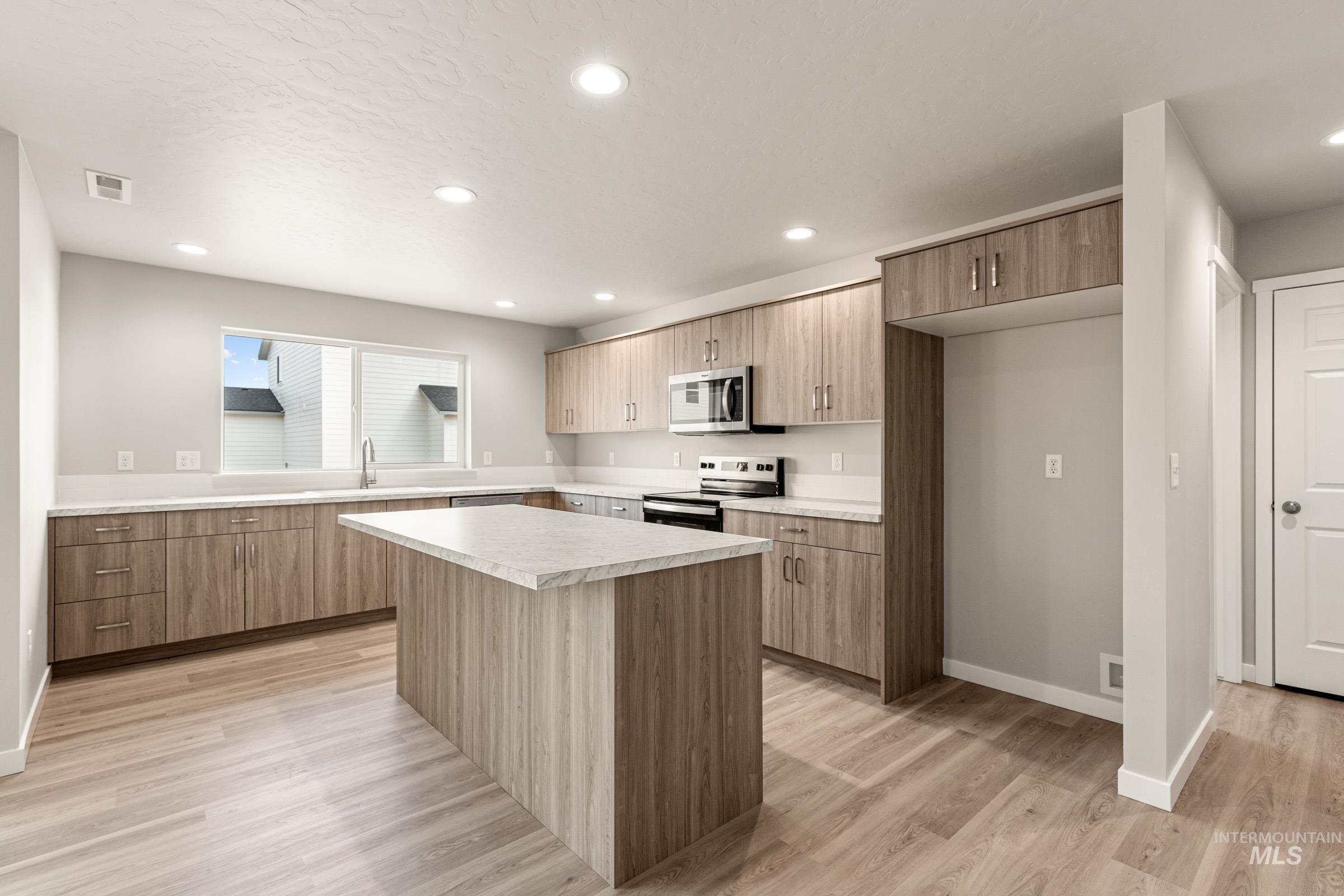 13686 Inman Court Caldwell, ID 83607 - Photo 3 of 20 Kitchen with stainless steel appliances, light countertops, light wood-style floors, a kitchen island, and modern cabinets