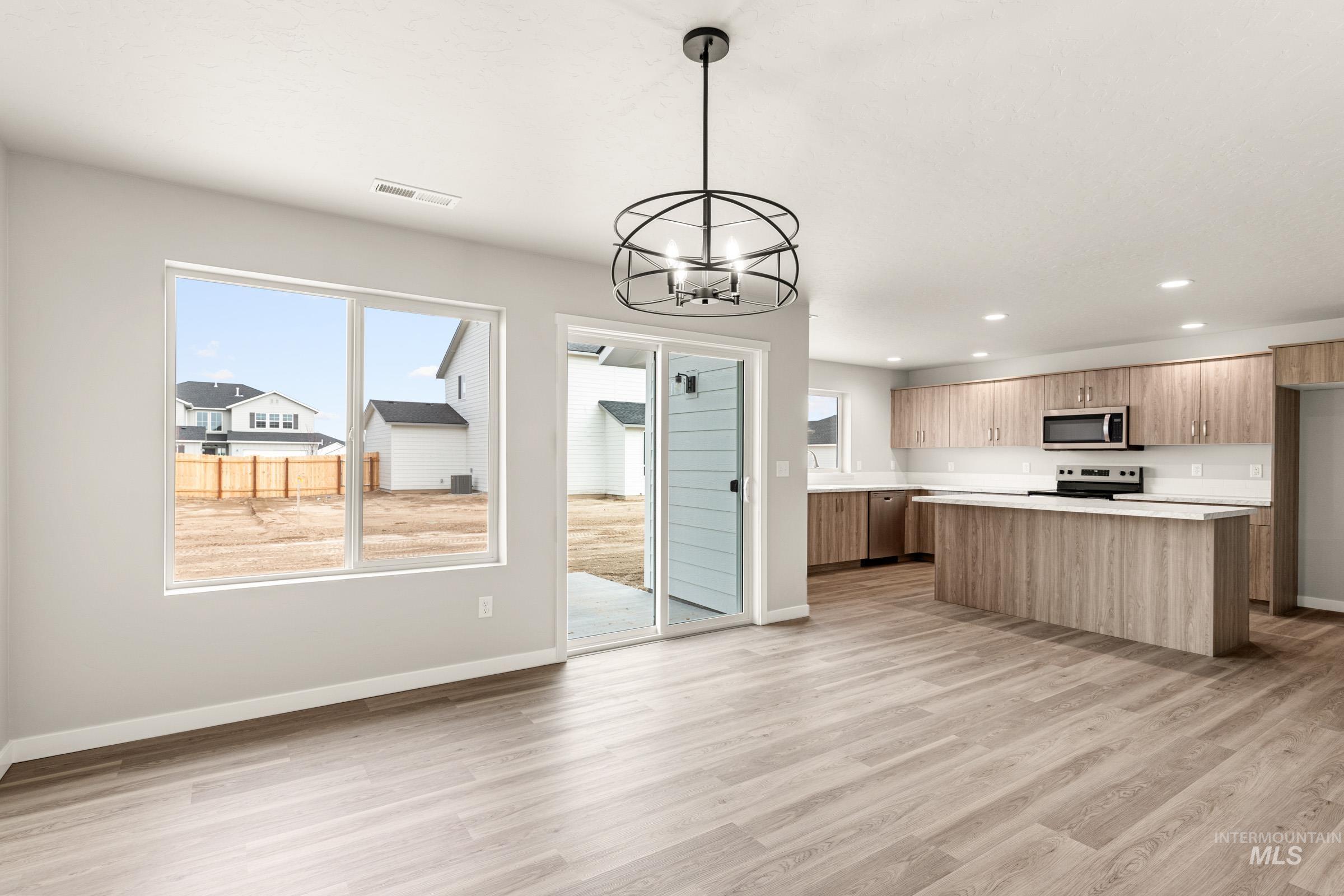 13686 Inman Court Caldwell, ID 83607 - Photo 6 of 20 Kitchen with light countertops, suspended lighting, a kitchen island, light wood-style floors, and stainless steel appliances