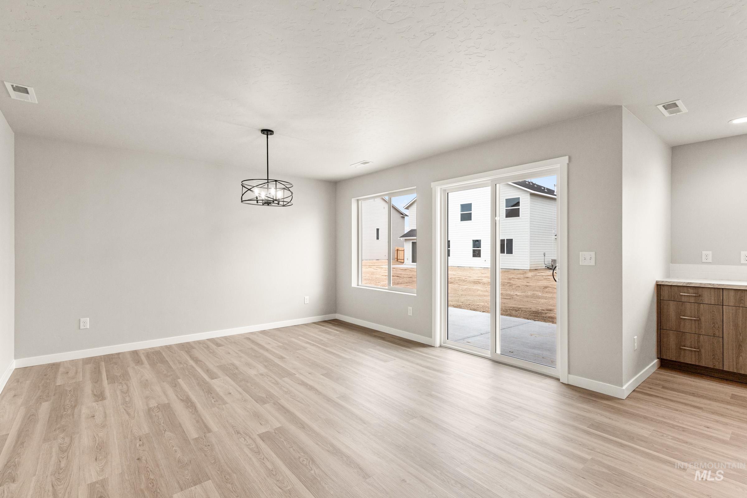 13686 Inman Court Caldwell, ID 83607 - Photo 7 of 20 Unfurnished dining area featuring light wood-style flooring, hanging lights, and a textured ceiling