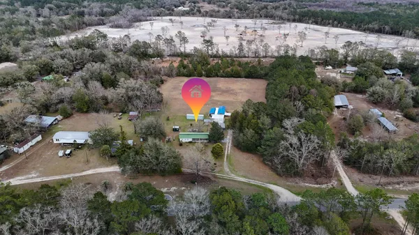 an aerial view of residential house with outdoor space and trees all around
