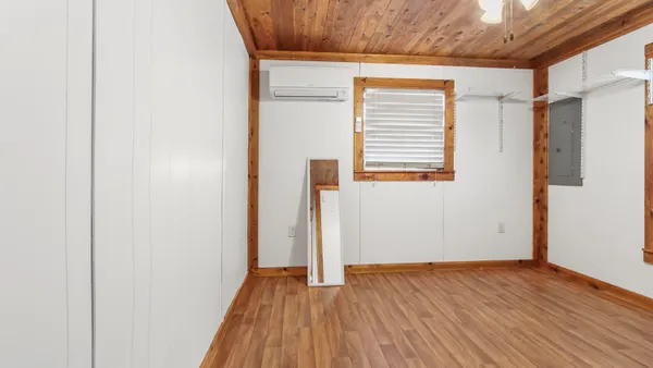 a view of a hallway with wooden floor and a bathroom