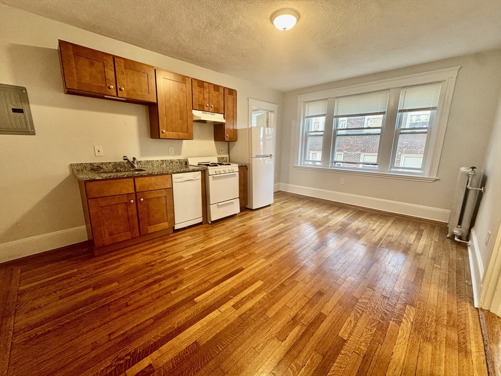 1615 Commonwealth Avenue, Unit 27 Boston, MA 02135 - Photo 3 of 10 a large kitchen with stainless steel appliances wooden floors and wooden cabinets