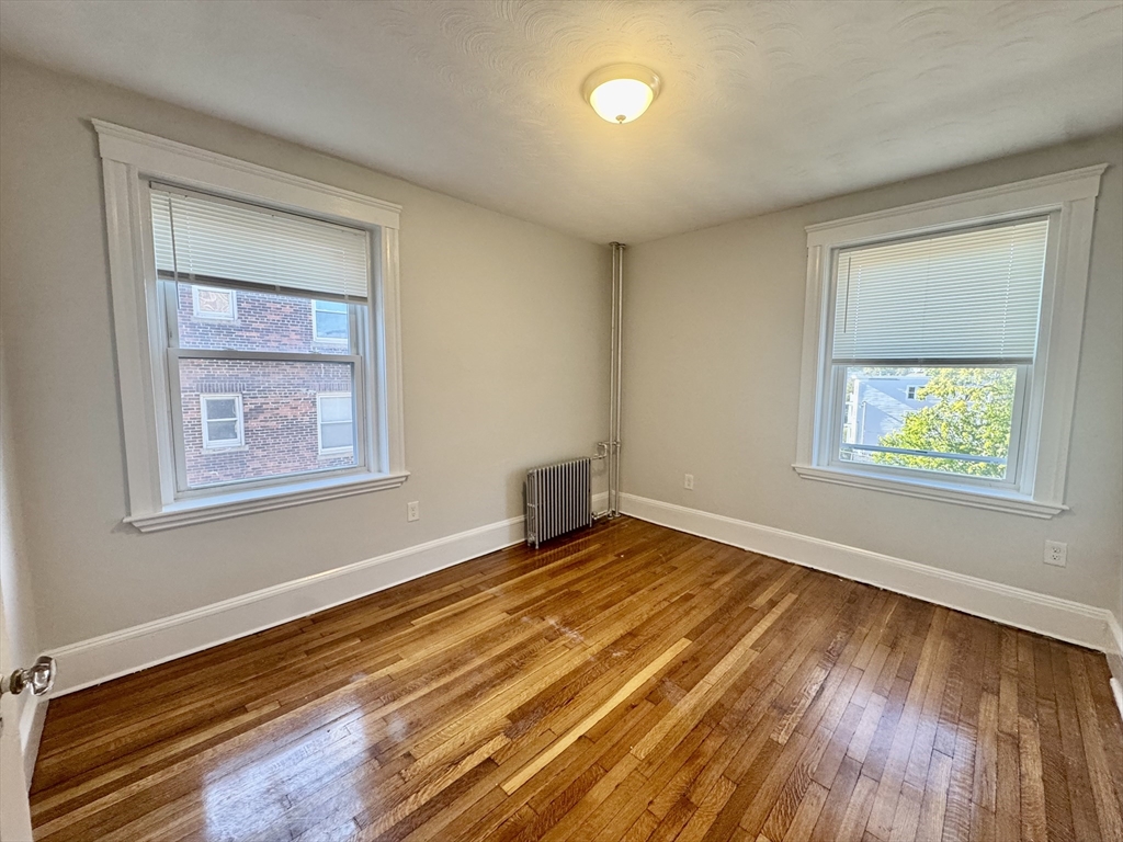 1615 Commonwealth Avenue, Unit 27 Boston, MA 02135 - Photo 5 of 10 a view of an empty room with wooden floor and a window