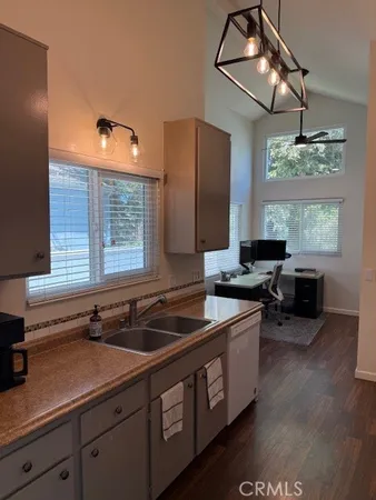 a kitchen with stainless steel appliances a sink dishwasher a stove a dining table and chairs with wooden floor