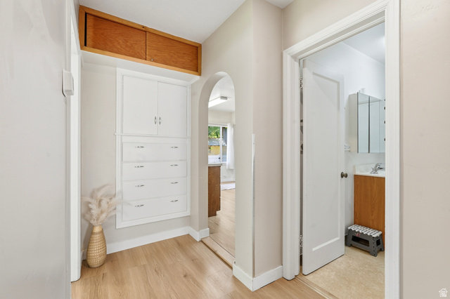 270 East 700 North Logan, UT 84321 - Photo 14 of 42 Hallway featuring built-in white cabinetry with drawers, wood-finish flooring, and an arched doorway leading to another room