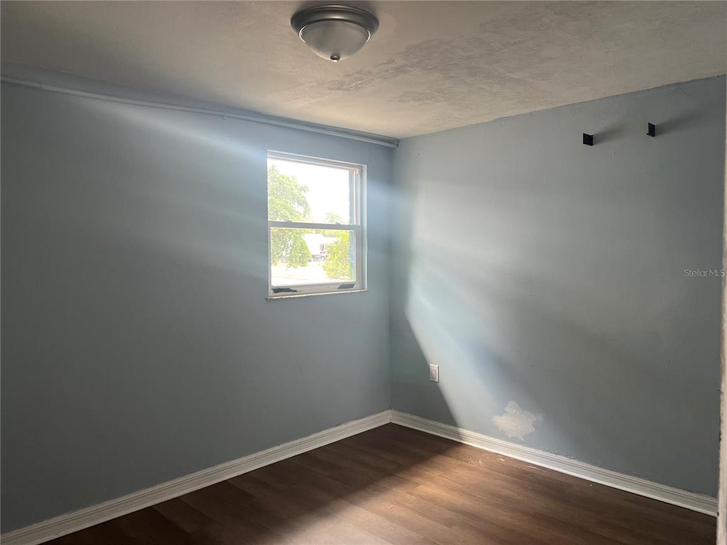 5206 7th Street Zephyrhills, FL 33542 - Photo 5 of 10 an empty room with wooden floor and windows