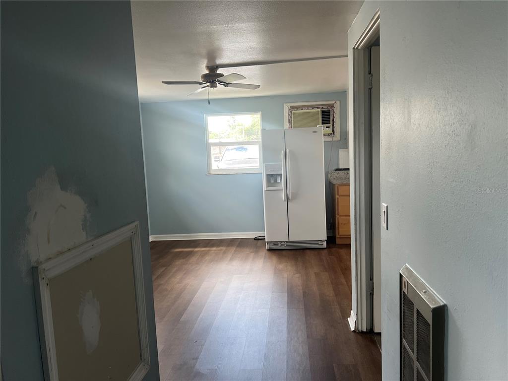 5206 7th Street Zephyrhills, FL 33542 - Photo 8 of 10 an empty room with wooden floor a ceiling fan and windows