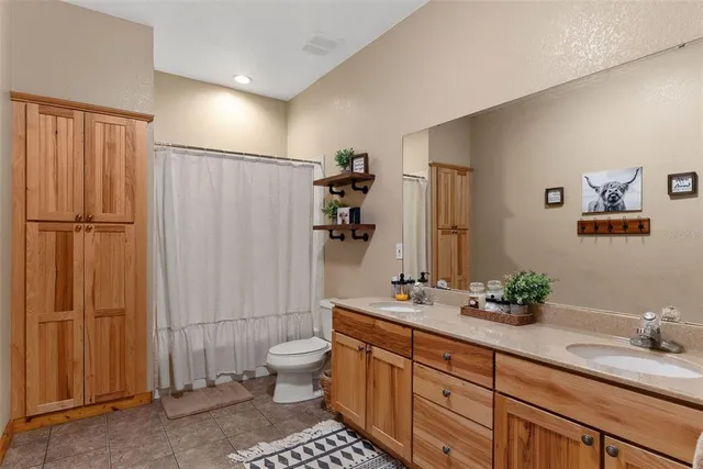 a bathroom with double vanity sinks a toilet a mirror and shower