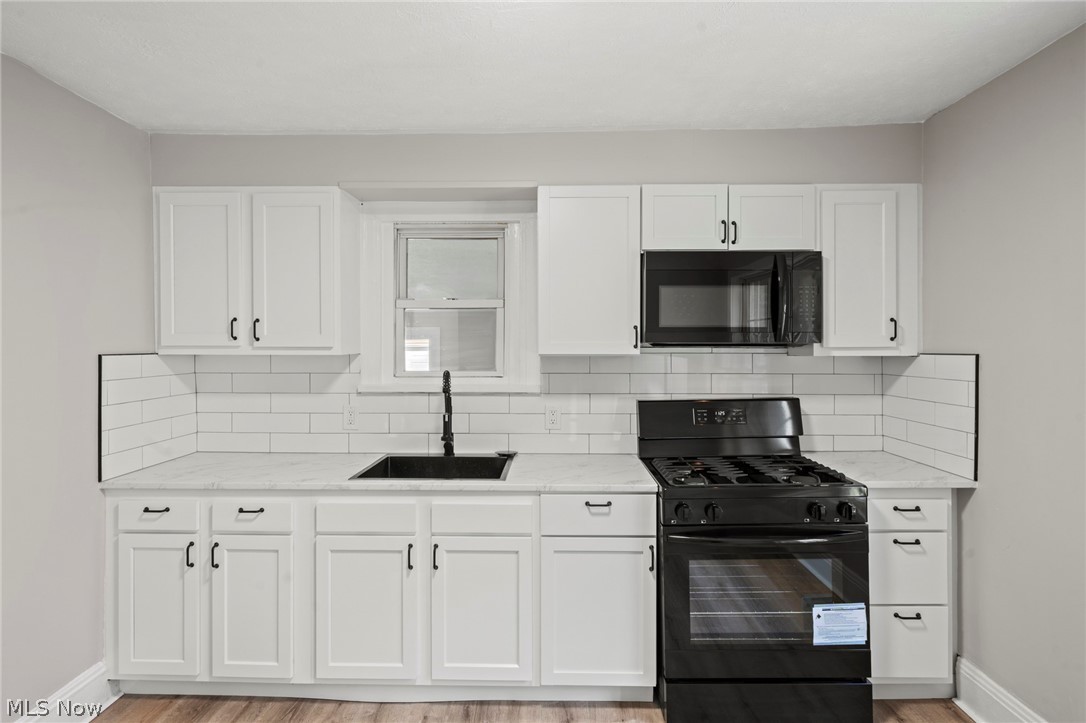1218 Briggle Road Akron, OH 44320 - Photo 14 of 40 Kitchen featuring white shaker-style cabinetry, a black range, a black microwave, a black sink, and white subway tile backsplash
