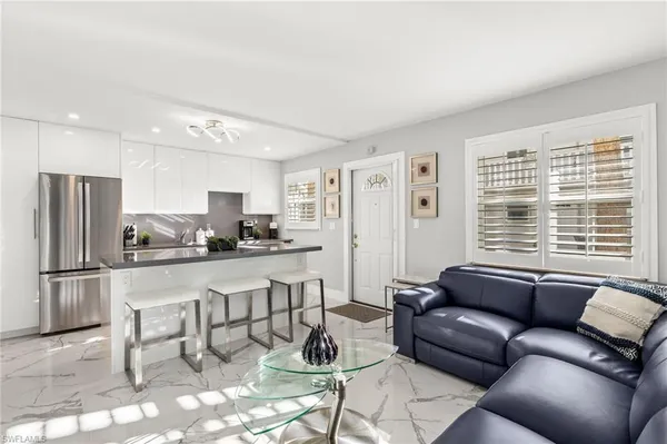 a living room with stainless steel appliances furniture and a kitchen view