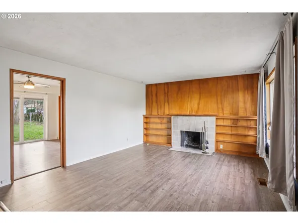 a view of empty room with wooden floor and fireplace