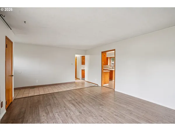 a view of an empty room with wooden floor and windows