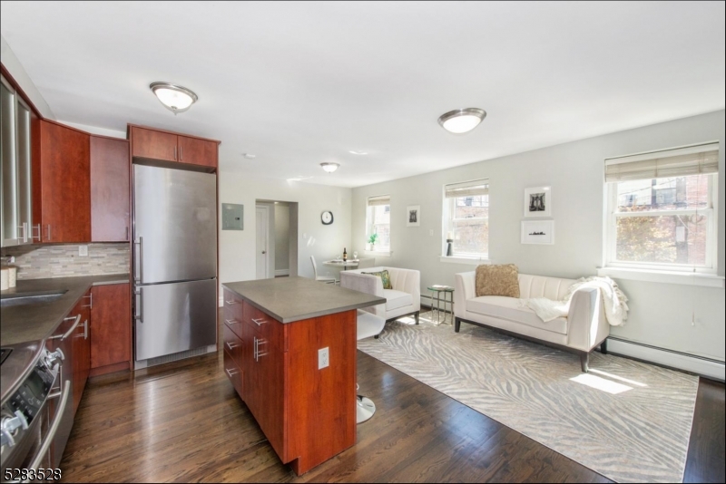a living room with stainless steel appliances granite countertop furniture wooden floor and a window