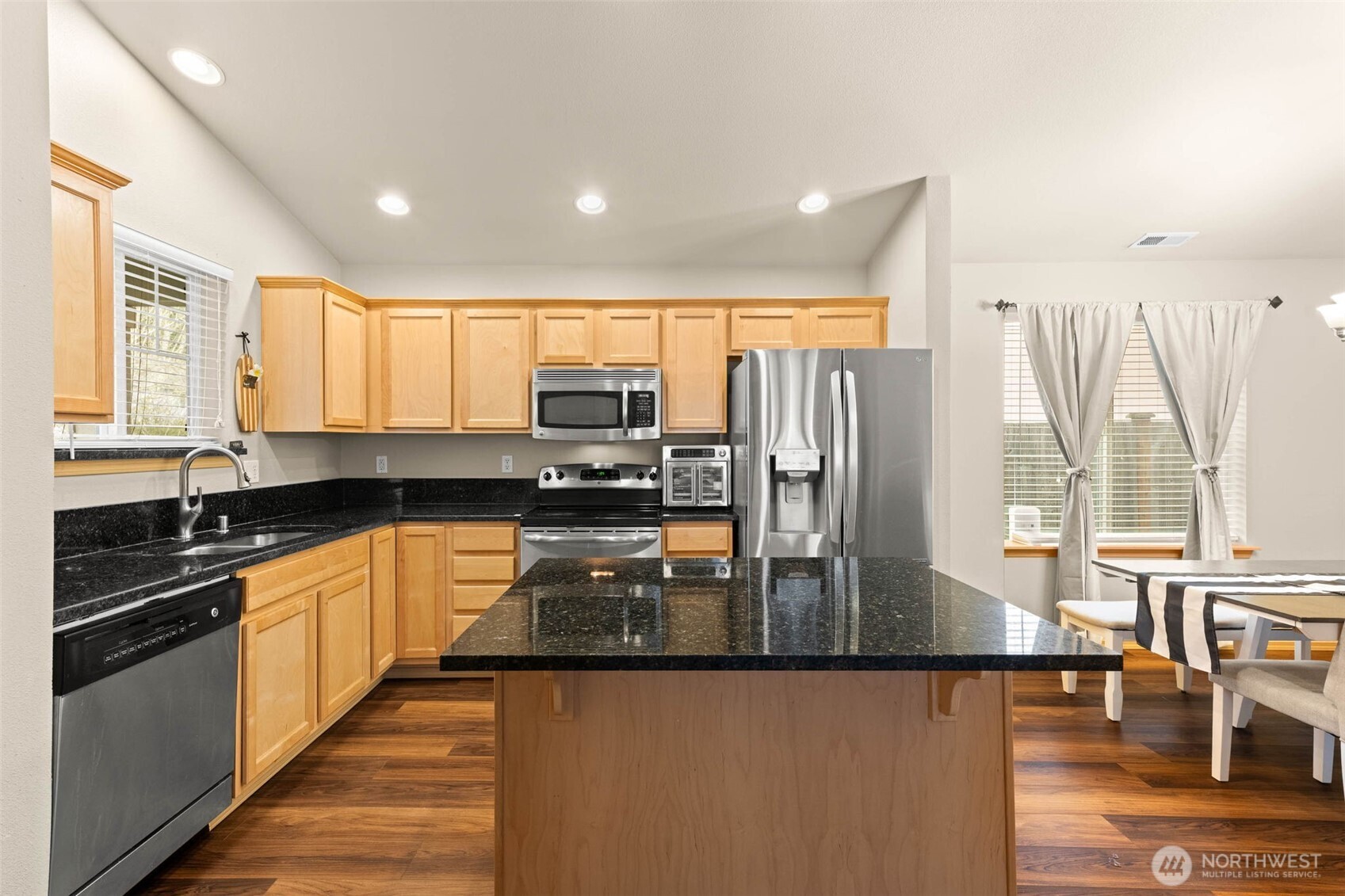20009 96th Avenue East Graham, WA 98338 - Photo 6 of 40 a kitchen with stainless steel appliances granite countertop a refrigerator a stove and a sink with wooden floor
