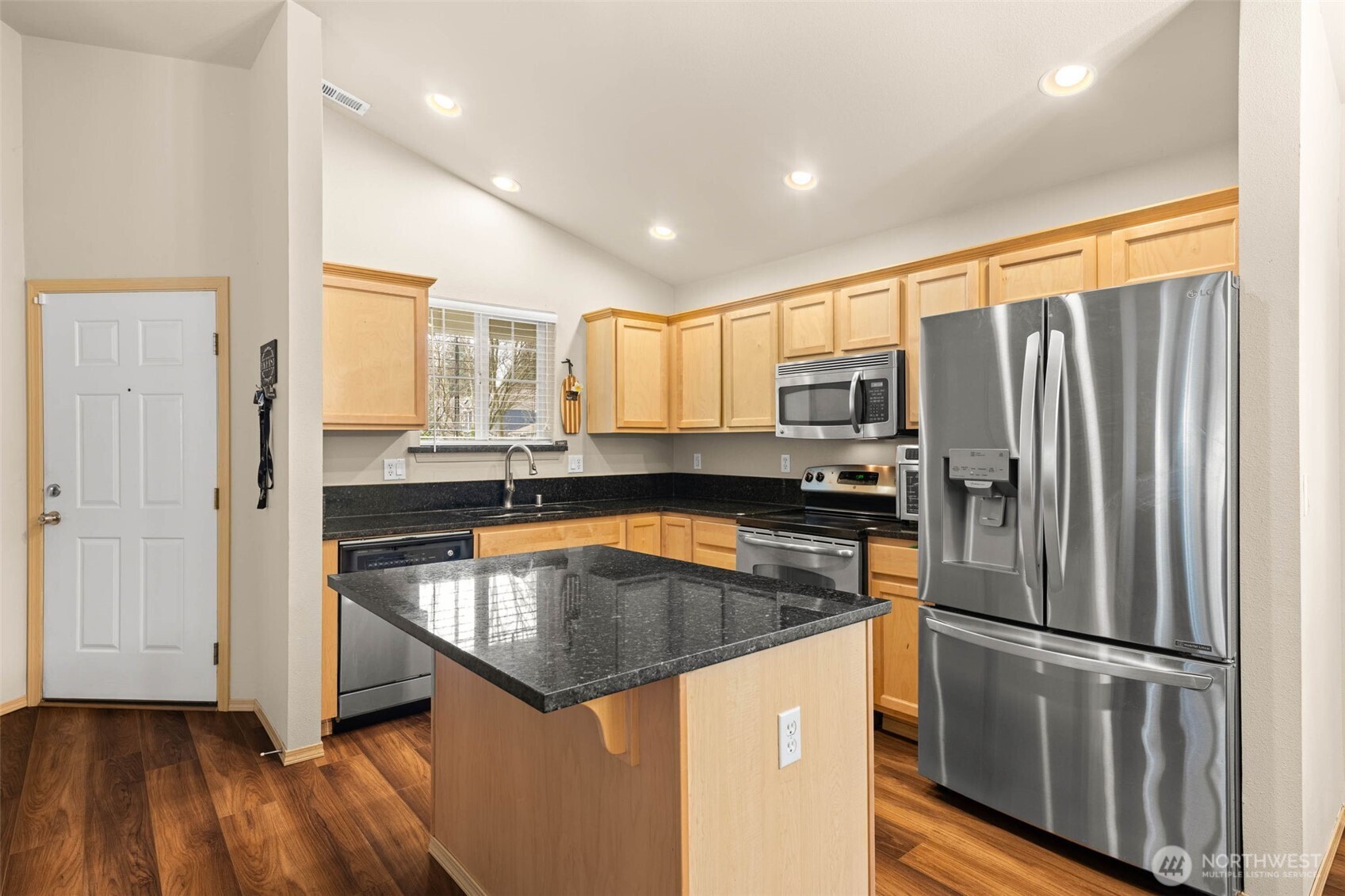 20009 96th Avenue East Graham, WA 98338 - Photo 7 of 40 a kitchen with granite countertop stainless steel appliances a refrigerator a stove top oven and wooden floors