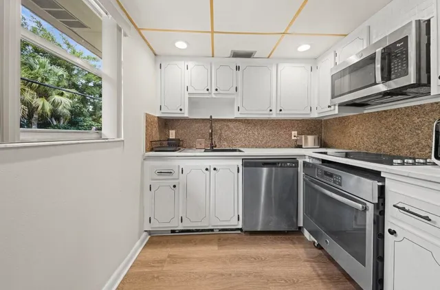 a kitchen with stainless steel appliances granite countertop a sink a stove a microwave and wooden cabinets