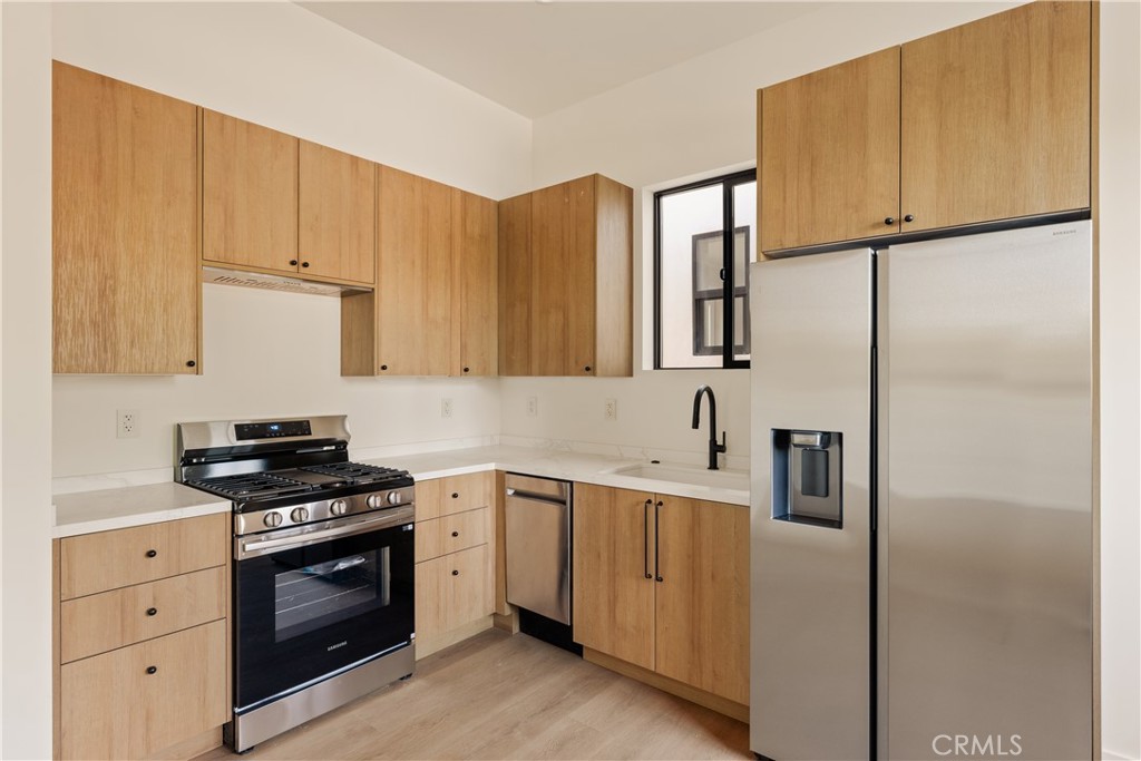 17852 Saticoy Street Reseda, CA 91335 - Photo 20 of 28 a kitchen with cabinets stainless steel appliances and wooden cabinets