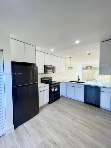 a kitchen with stainless steel appliances kitchen island granite countertop a refrigerator stove and sink