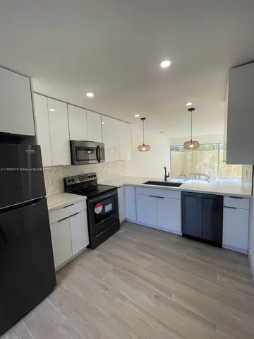 a kitchen with granite countertop a refrigerator stove top oven and sink