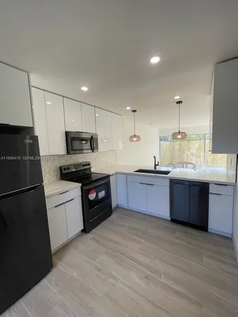 a kitchen with granite countertop a refrigerator stove top oven and sink