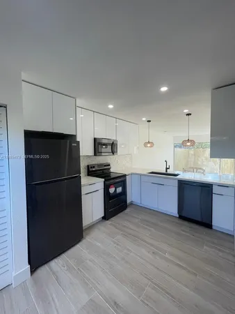 a kitchen with stainless steel appliances kitchen island granite countertop a refrigerator a sink dishwasher a stove top oven and a refrigerator