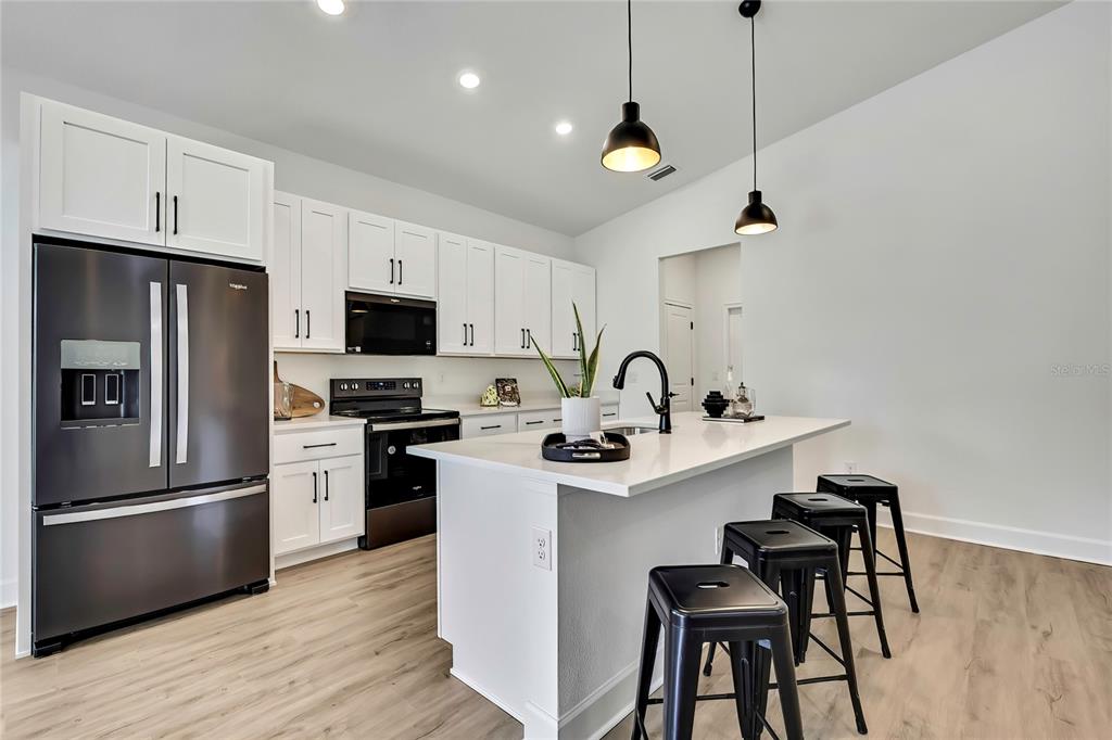 6589 Freeport Drive Spring Hill, FL 34608 - Photo 7 of 57 a kitchen with stainless steel appliances granite countertop a sink a stove a refrigerator and island with wooden floor
