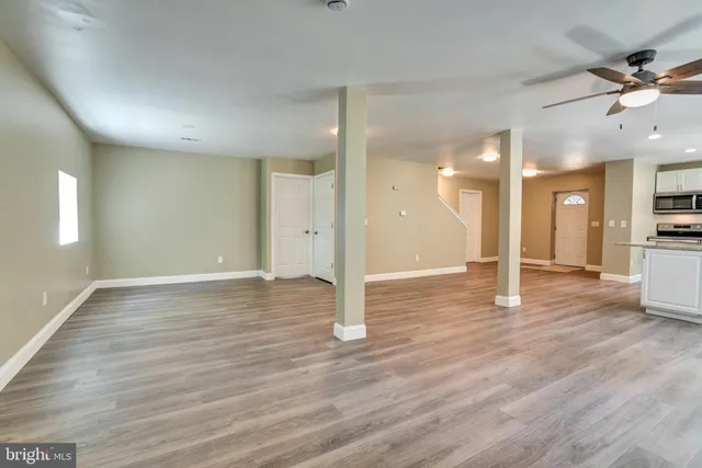 a view of a big room with wooden floor and a kitchen