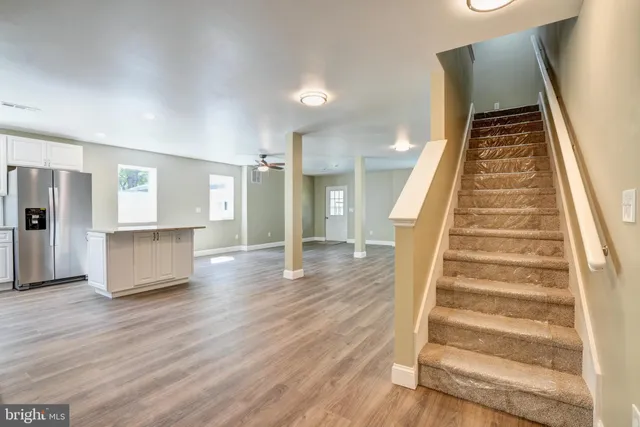 a view of a kitchen with a sink a refrigerator and wooden floor