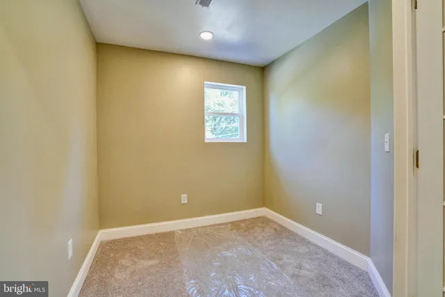 a view of an empty room with wooden floor and a bathroom