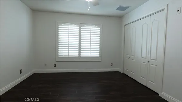 an empty room with wooden floor closet fan and windows