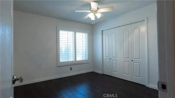 an empty room with wooden floor fireplace and windows