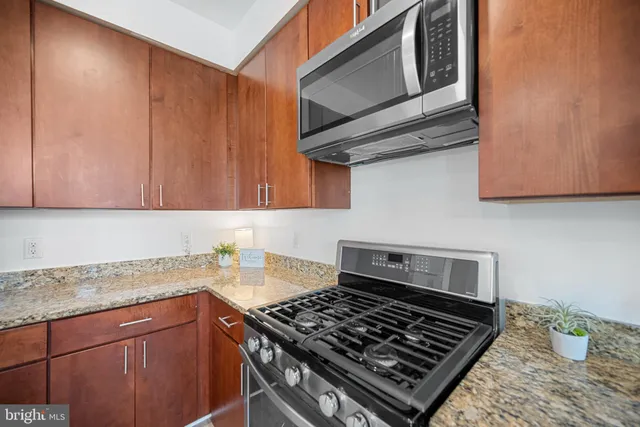 a kitchen with granite countertop stainless steel appliances stove top oven and cabinets