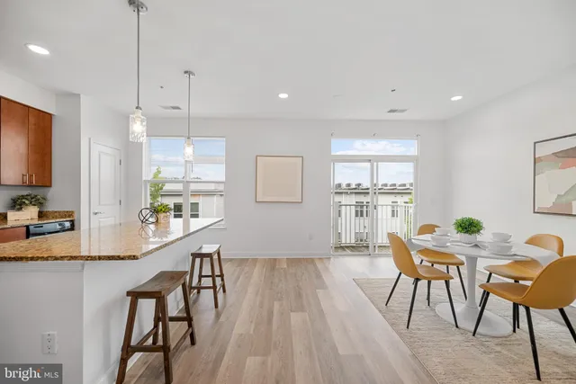 a view of a kitchen with kitchen island granite countertop wooden floor and stainless steel appliances