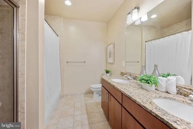 a bathroom with a granite countertop sink a toilet and a mirror