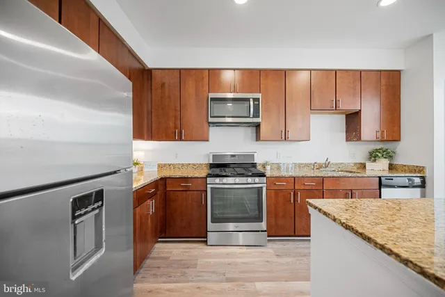 a kitchen with stainless steel appliances granite countertop a stove a sink and a microwave