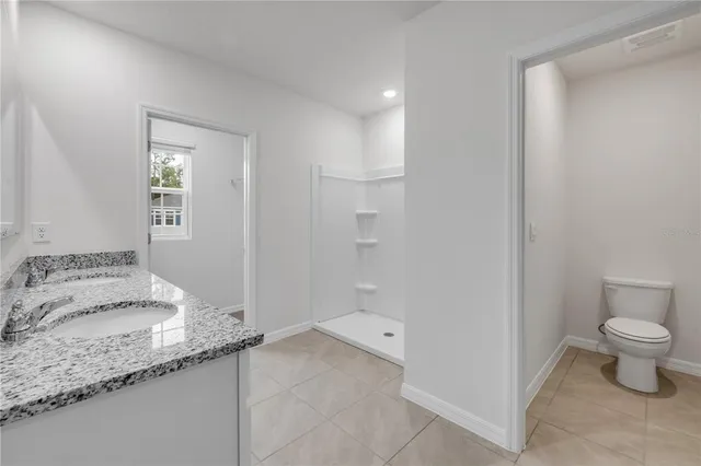 a bathroom with a granite countertop sink and a toilet