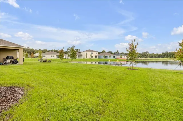 a view of house that has a big yard with large trees