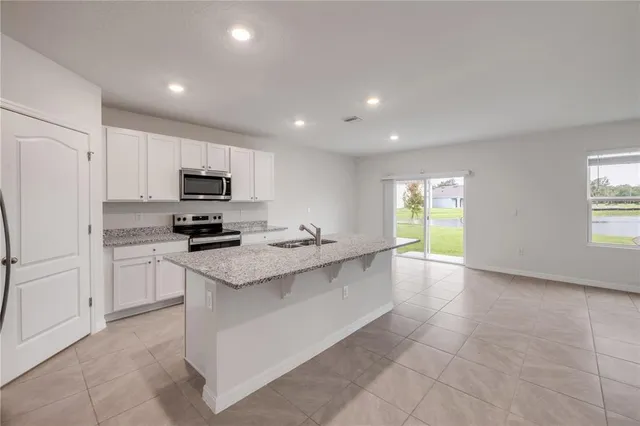 a kitchen with stainless steel appliances a sink a stove a refrigerator cabinets and a window