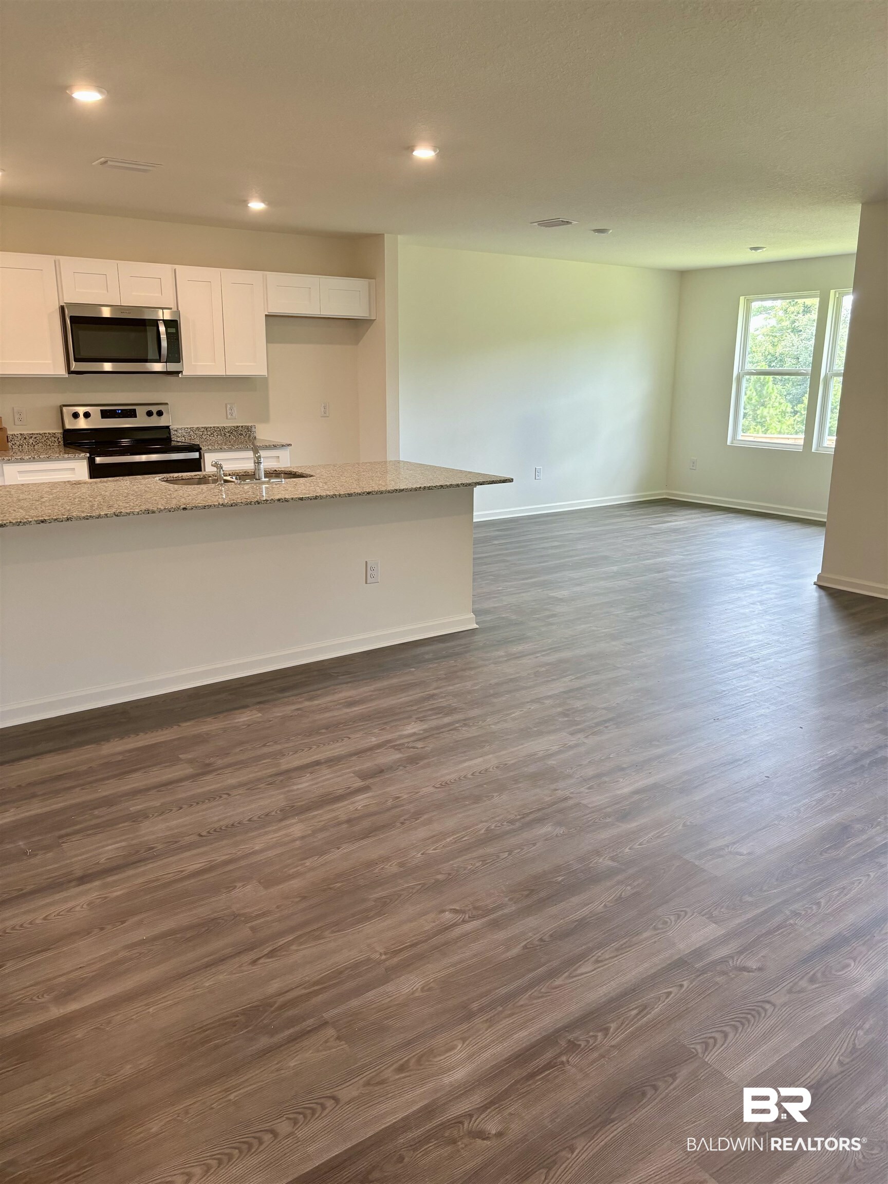 21695 Sutherland Circle Fairhope, AL 36532 - Photo 2 of 9 Kitchen featuring light stone counters, stainless steel appliances, white cabinetry, sink, and dark wood-type flooring