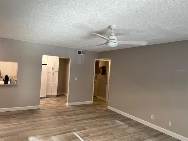 an empty room with wooden floor and ceiling fan
