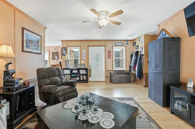 a living room with furniture a flat screen tv and a refrigerator